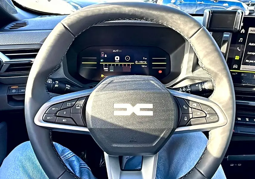 Vue rapprochée du volant noir multifonction et du tableau de bord numérique du Dacia Duster 2026.