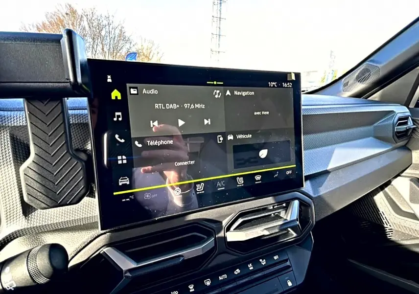 Vue intérieure du tableau de bord du Dacia Duster 2026 noir, avec écran tactile multifonction et aérateurs angulaires.