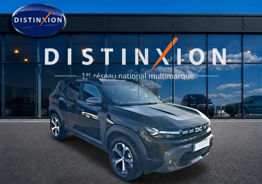 Dacia Duster noir en 3/4 avant droit, avec jantes alu et barres de toit, devant une vitrine Distinxion.