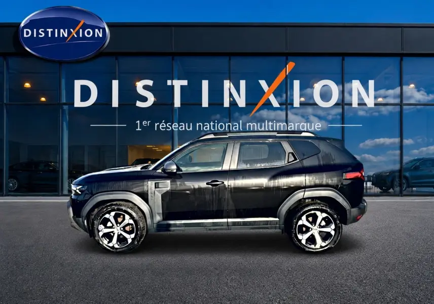 Profil côté gauche du Dacia Duster noir 2026 avec jantes alu, garé devant une vitrine Distinxion.