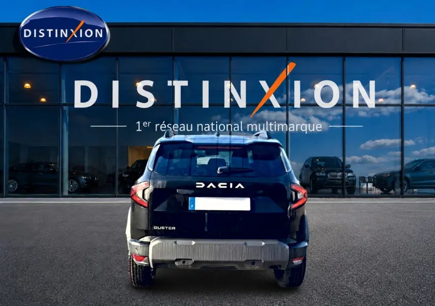 Vue arrière d'un Dacia Duster noir 2026, avec barres de toit et logo distinctif sur fond de vitrine Distinxion.