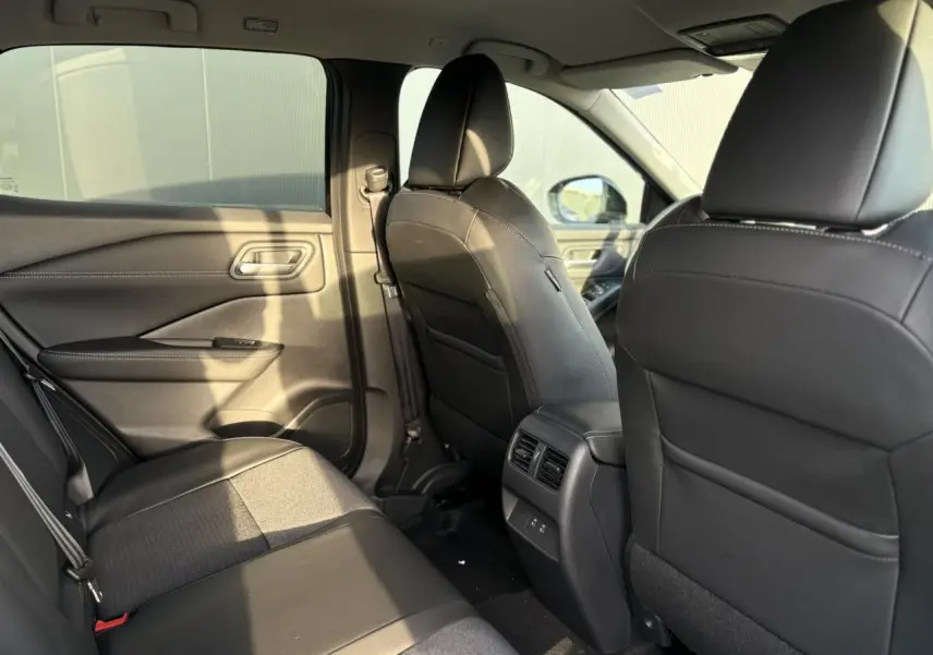 Vue intérieure arrière côté gauche du Nissan Qashqai noir Kuro, montrant les sièges et la console centrale avec aérateurs.
