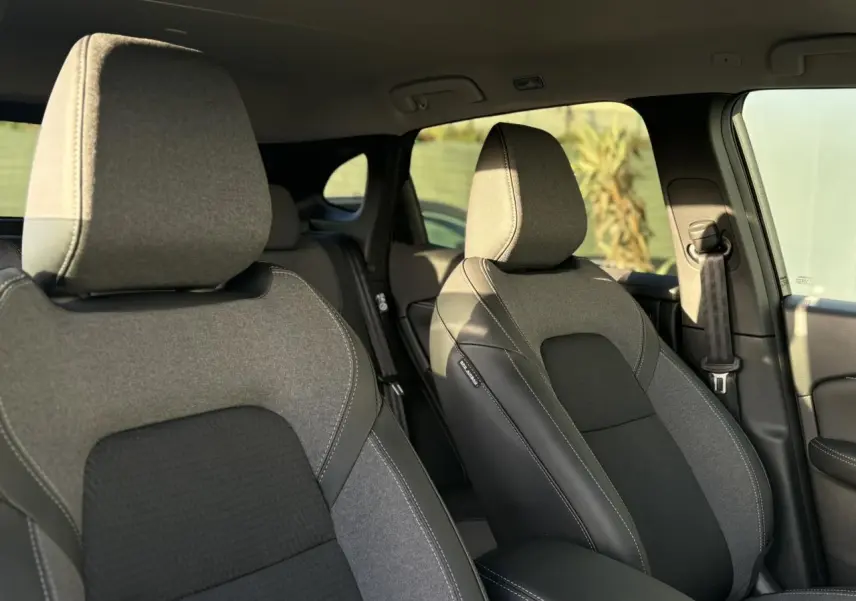 Vue intérieure des sièges avant gris et noirs du Nissan Qashqai III e-Power 2026, avec accoudoir central visible.