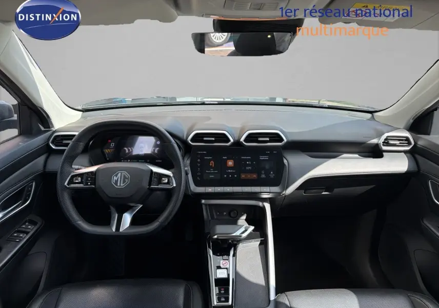 Vue intérieure frontale du tableau de bord du MG MOTOR ZS 2025 en gris, avec écran tactile central et volant multifonction cuir.