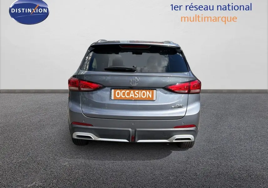 Vue arrière d’un MG ZS 1.5L Hybrid+ 197ch Luxury en gris Hampstead avec feux LED et double sortie d’échappement intégrée.
