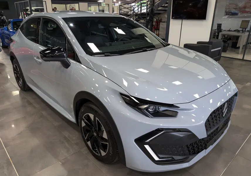 Renault Clio VI gris Rafale vue 3/4 avant droit, avec jantes noires bicolores et rétroviseurs noirs brillants.