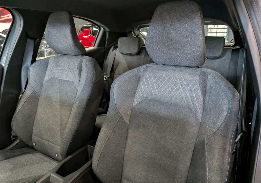 Vue intérieure sur les sièges avant en tissu gris de la Renault Clio VI 1.2 TCe 115 CH Evolution, avec détails de couture bleue.