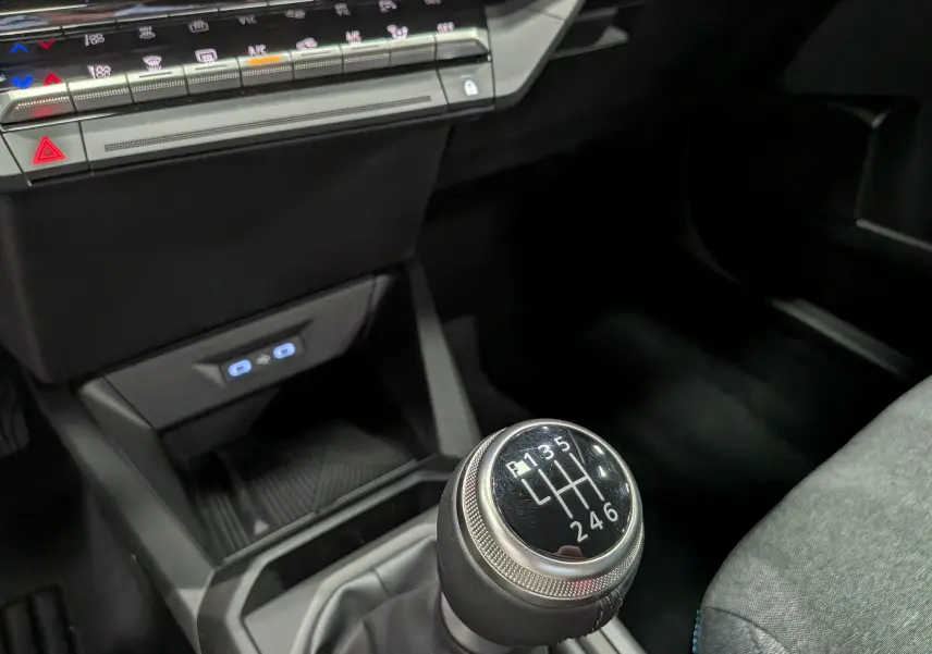 Gros plan sur le levier de vitesses manuel 6 rapports de la Renault Clio VI 1.2 TCe 115 Gris Rafale, intérieur noir et tissu gris.