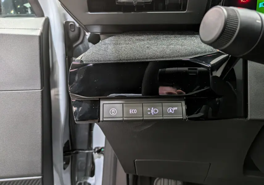 Vue rapprochée côté gauche du tableau de bord gris et noir de la Renault Clio VI avec boutons de contrôle éclairés.