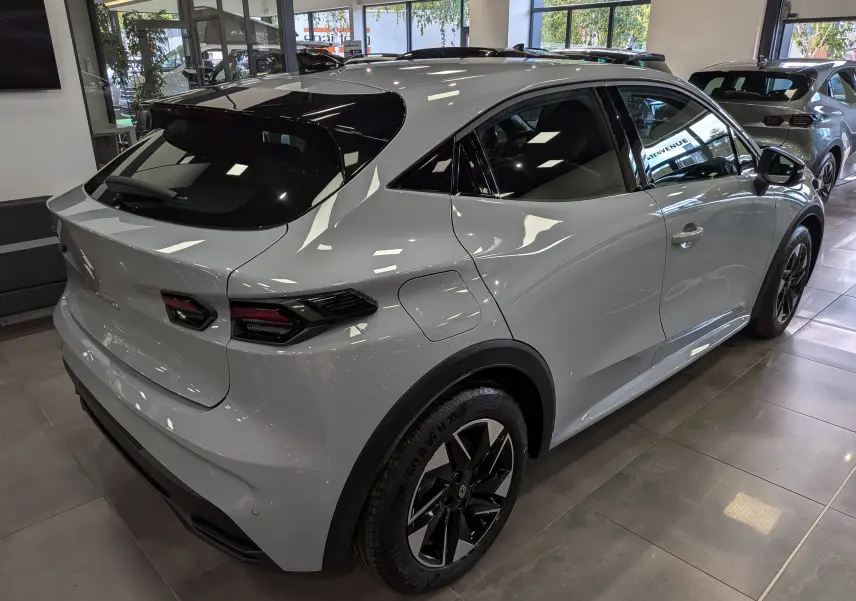 Vue 3/4 arrière droite d'une Renault Clio VI gris Rafale avec jantes biton et vitres teintées en showroom.
