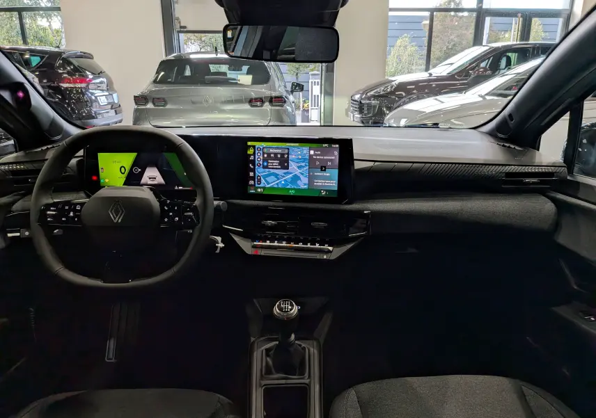 Vue intérieure avant de la Renault Clio VI gris Rafale, avec tableau de bord numérique et écran central tactile.