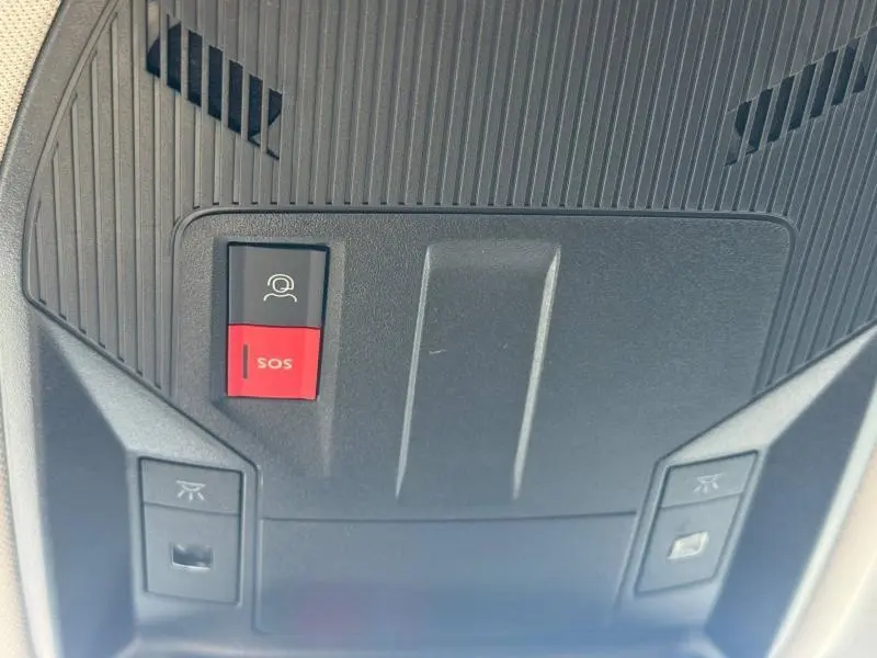 Gros plan sur la console de plafond de la Peugeot 308 2024, montrant les boutons SOS et assistance en rouge et noir.