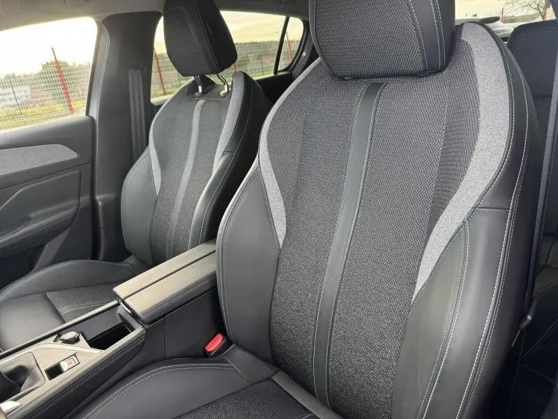 Gros plan sur les sièges avant en tissu et cuir noir avec surpiqûres blanches de la Peugeot 308 2024 Gris Artense.