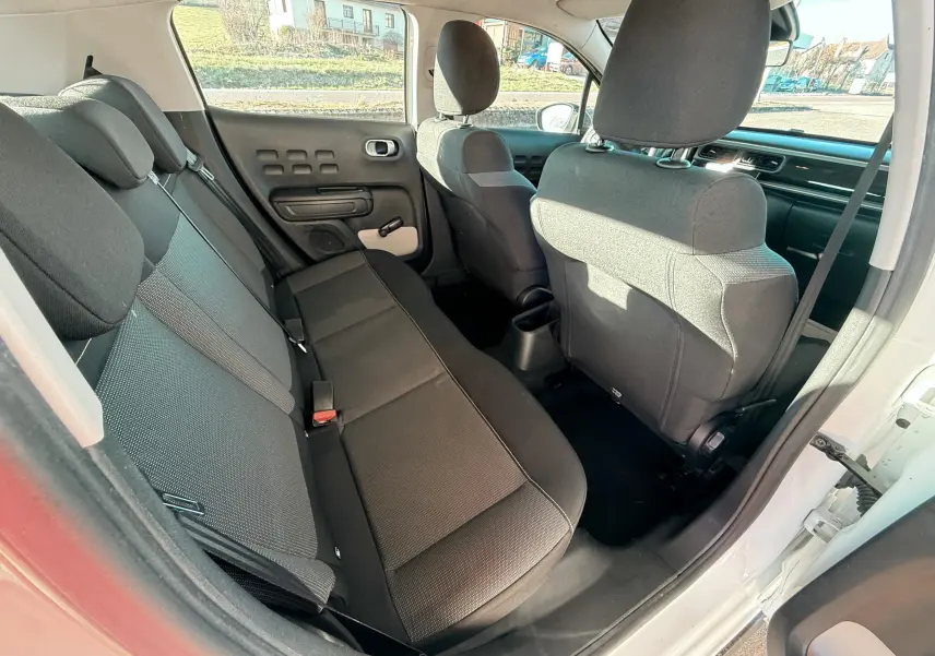 Vue intérieure arrière côté droit d'une Citroën C3 blanche de 2017, sièges tissu gris foncé et noir.