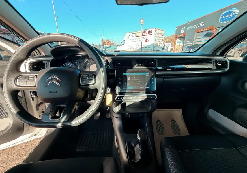 Vue intérieure avant de la Citroën C3 blanche 2017, tableau de bord avec écran tactile et volant multifonction.