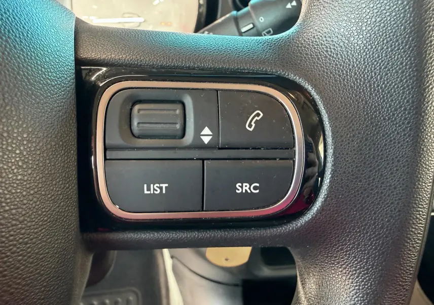 Gros plan sur les boutons de commande audio et téléphone sur le volant noir d'une Citroën C3 2017.
