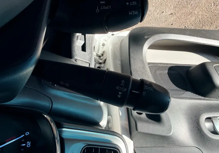 Gros plan sur la manette de clignotants côté gauche d’une Citroën C3 blanche, intérieur gris noir visible.
