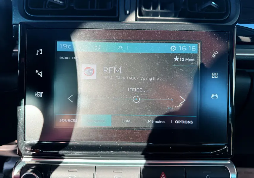 Écran tactile central de la Citroën C3 2017 affichant la radio RFM, avec commandes tactiles et boutons de climatisation.
