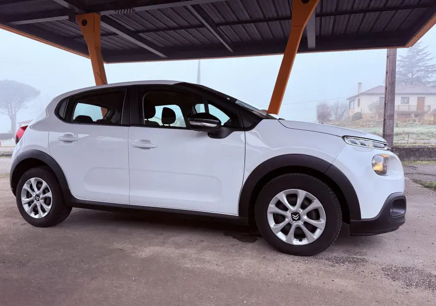 Vue latérale droite d'une Citroën C3 blanche de 2017, avec jantes argentées et protections noires sur les passages de roues.