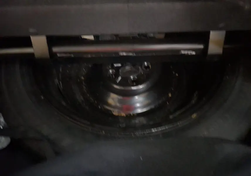 Gros plan sur la roue de secours sous le coffre du Renault Espace blanc nacré, version hybride 7 places 2025.