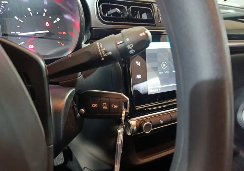Vue rapprochée de l'intérieur côté conducteur de la Citroën C3 gris clair, avec clé insérée et écran tactile central allumé.
