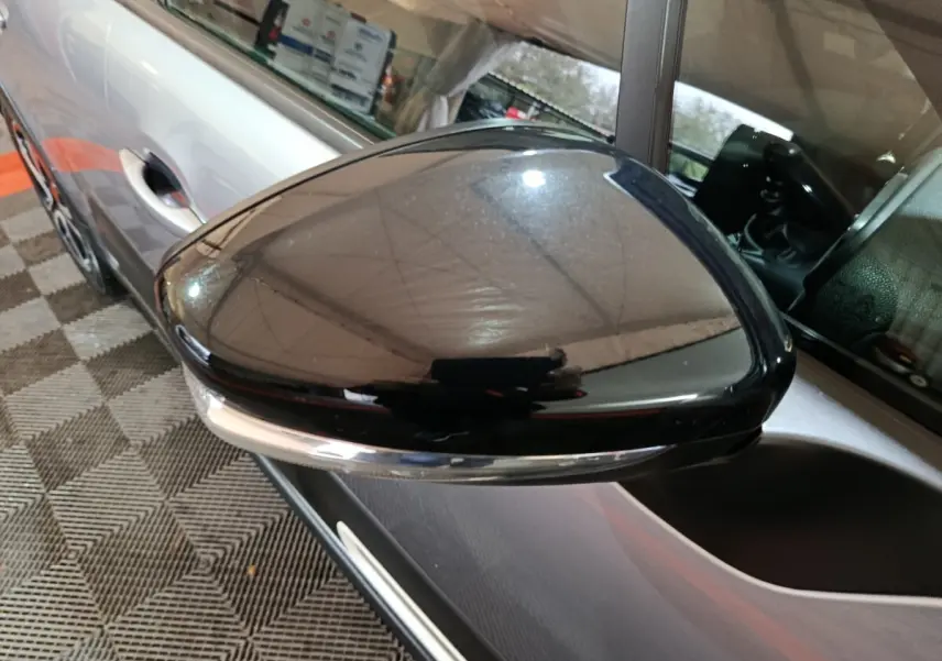 Rétroviseur droit noir brillant avec caméra sur Citroën C3 gris clair, vue rapprochée côté conducteur.