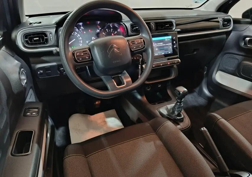 Intérieur avant de la Citroën C3 gris clair, vue côté conducteur, volant multifonctions et écran tactile central visible.