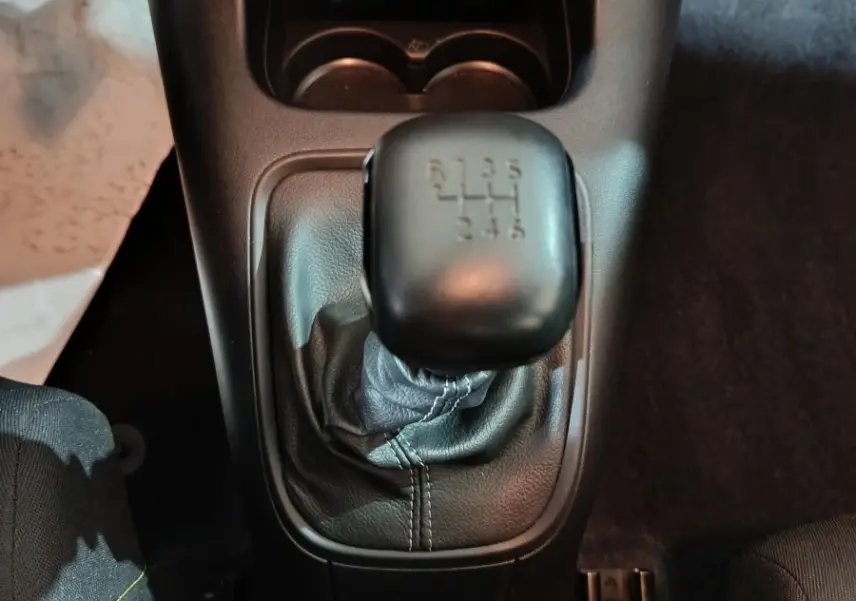 Vue plongeante sur le levier de vitesses manuel noir de la Citroën C3 2024, avec console centrale et porte-gobelets.