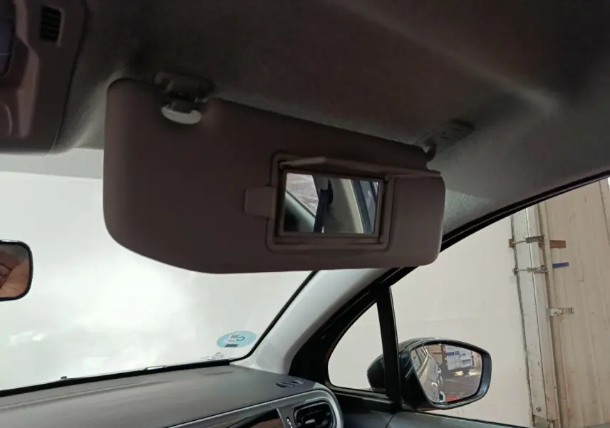 Vue intérieure côté conducteur du pare-soleil avec miroir intégré et rétroviseur extérieur noir d'une Citroën C3 gris clair.