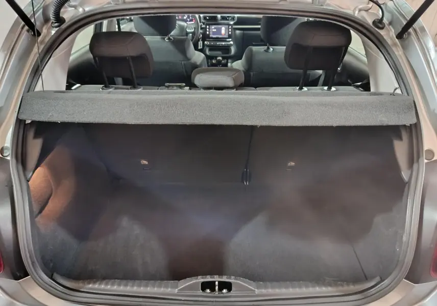 Vue arrière du coffre ouvert d'une Citroën C3 gris clair 2024, avec banquette arrière et tableau de bord visibles.