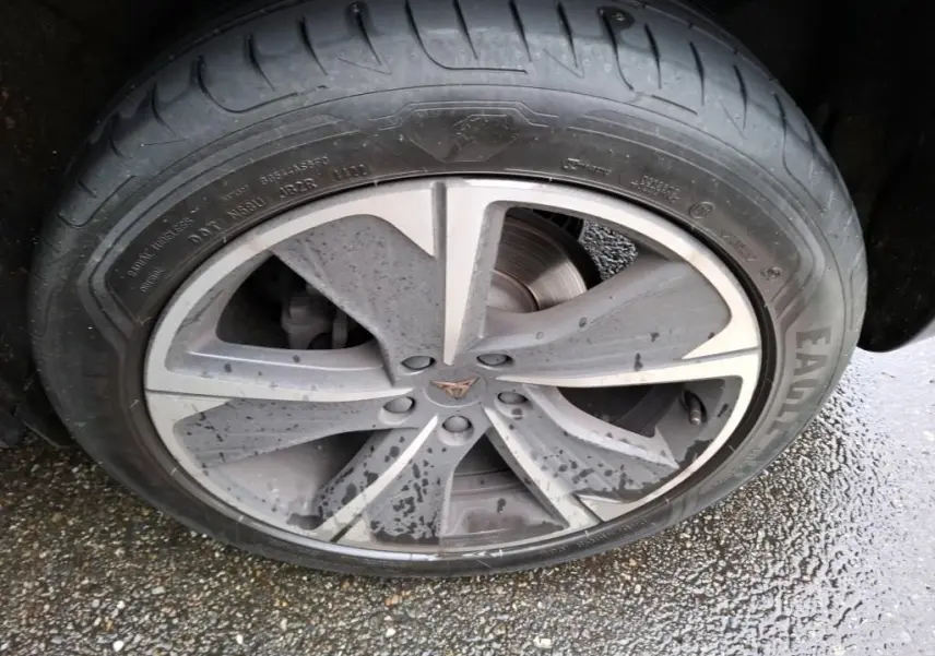 Gros plan sur la jante alu grise avec logo CUPRA au centre, roue arrière d'un CUPRA Formentor noir sous la pluie.