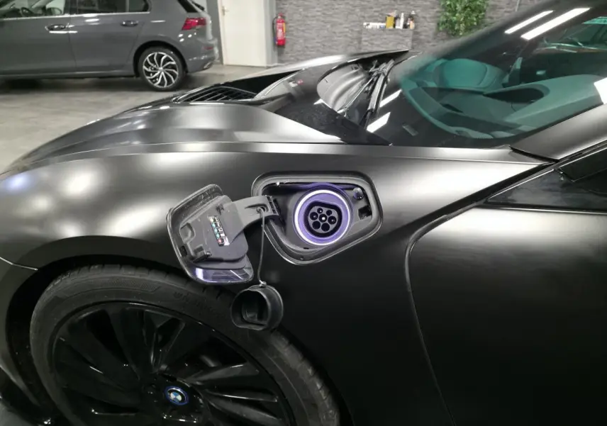 Prise de recharge ouverte côté gauche sur BMW i8 Coupé Pure Impulse noir mat, avec jante noire profilée 20 pouces visible.
