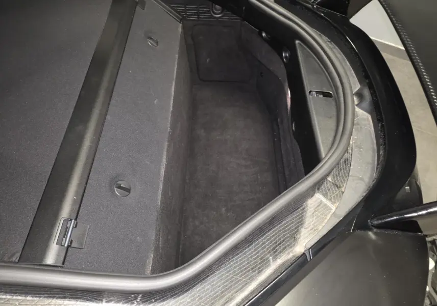Coffre arrière ouvert vu de dessus sur BMW i8 noir mat, montrant l'espace de rangement et les finitions intérieures.
