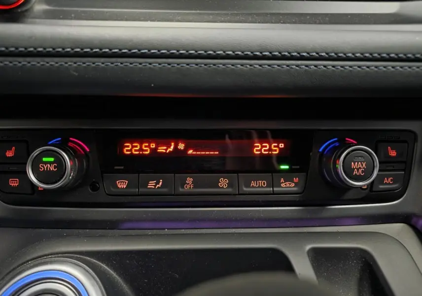 Détail de la console centrale de la BMW i8 noire, affichant la climatisation automatique à 22,5°C avec commandes rétroéclairées.