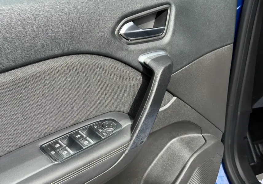 Gros plan sur la porte intérieure côté conducteur du Renault Symbioz bleu, avec commandes de vitres et poignée noire.