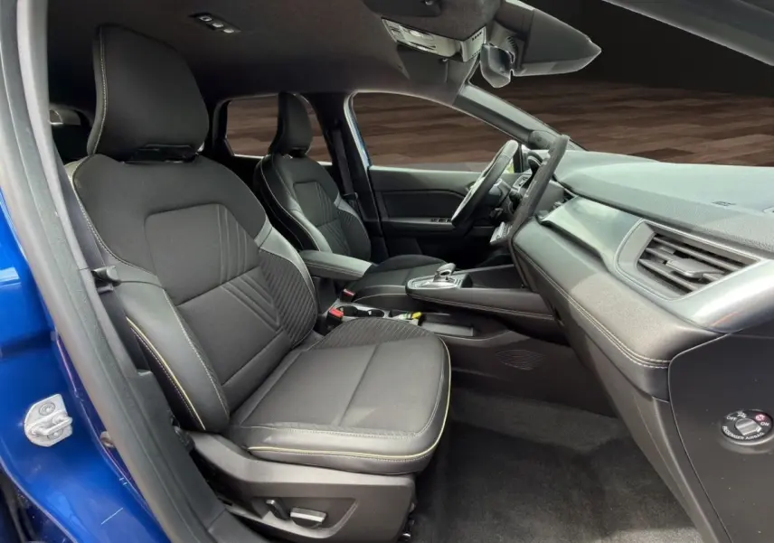 Intérieur avant droit de la Renault SYMBIOZ bleu 2025, sièges noirs avec surpiqûres, tableau de bord moderne et volant multifonctions.