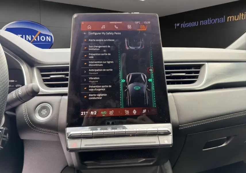 Vue intérieure du tableau de bord de la Renault Symbioz bleu, avec écran tactile central affichant les aides à la conduite.