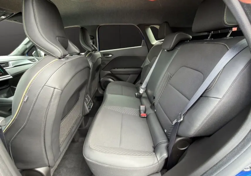 Vue intérieure arrière droite des sièges noirs en cuir et tissu du Renault Symbioz bleu, avec ceinture de sécurité visible.