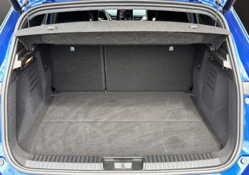 Vue arrière du coffre ouvert d'une Renault SYMBIOZ bleu, montrant l'espace de chargement et la tablette arrière.