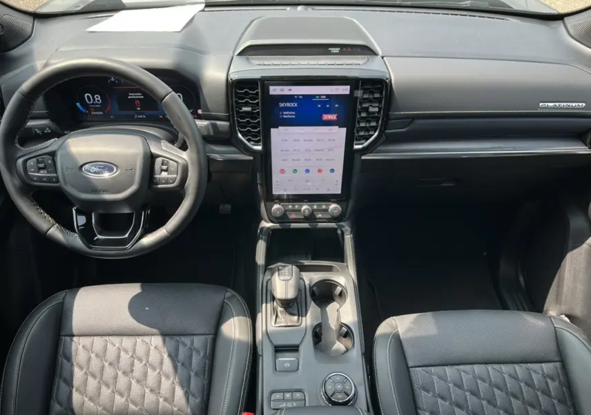 Vue intérieure avant du Ford Ranger Platinum 2026, tableau de bord noir avec écran tactile vertical et volant cuir multifonctions.