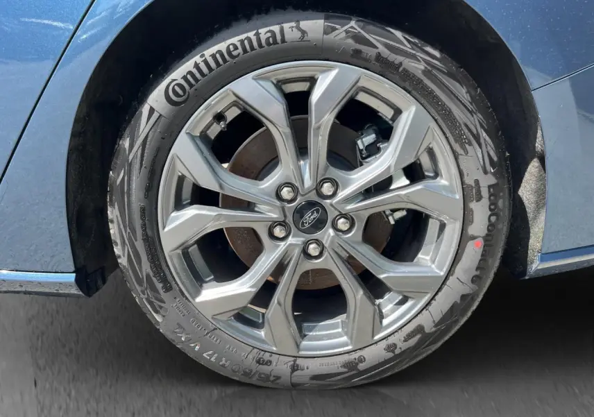 Gros plan sur la roue avant droite d’une Ford Focus SW bleue 2025 avec jante alliage et pneu Continental.