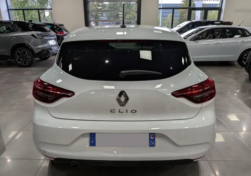Vue arrière d'une Renault Clio V blanche Glacier, avec feux arrière LED et vitre arrière teintée, en intérieur showroom.