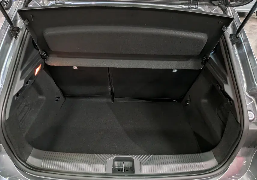 Coffre ouvert vu de l'arrière d'une Renault Clio VI gris schiste, montrant un espace de rangement propre et vide.