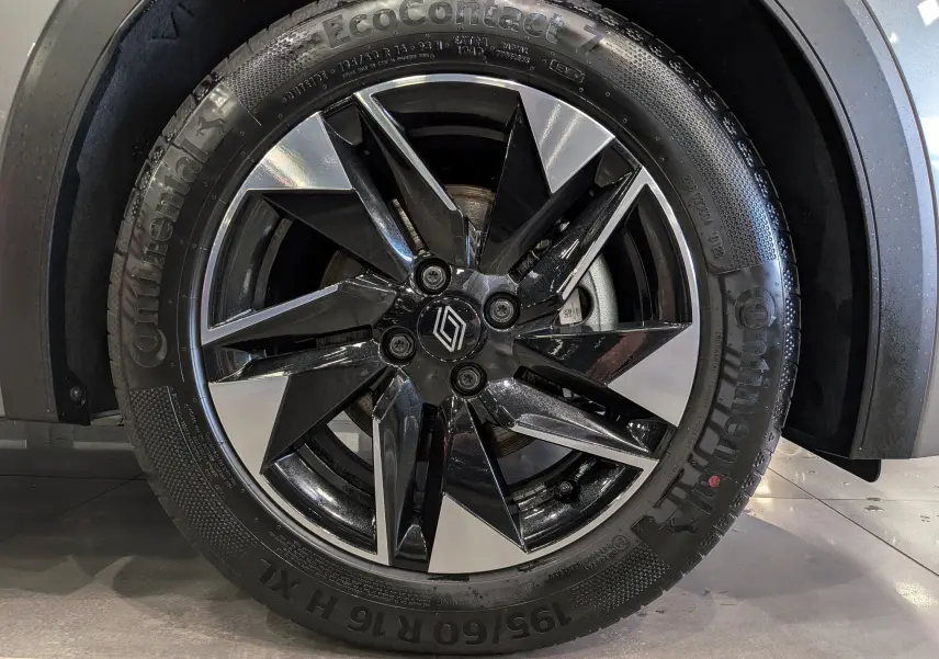 Gros plan sur la roue avant droite de la Renault Clio VI gris schiste, jante alliage bicolore avec logo Renault central.