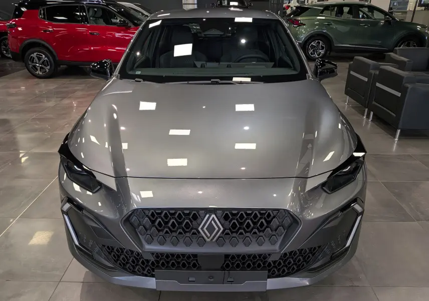 Vue avant plongeante d'une Renault Clio VI gris schiste, mettant en valeur sa calandre hexagonale et ses optiques anguleuses.