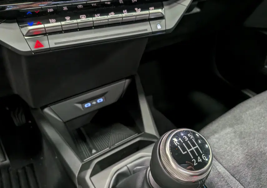 Gros plan sur la console centrale et le levier de vitesse manuel de la Renault Clio VI gris schiste, avec commandes climatisation visibles.
