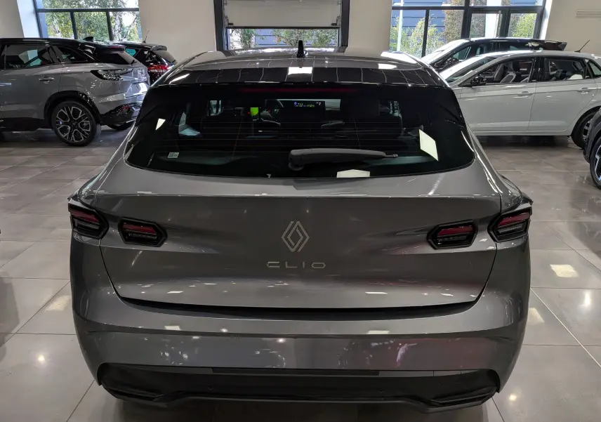 Vue arrière d'une Renault Clio VI gris schiste, avec feux arrière LED et lunette arrière teintée en showroom.