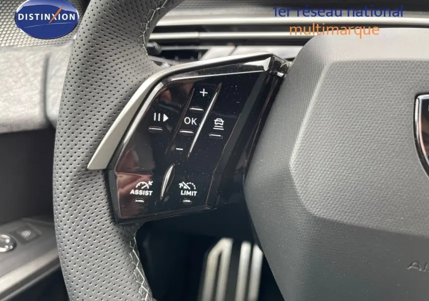 Gros plan sur les commandes à gauche du volant perforé du Peugeot 5008 Hybrid 2025 avec finition noire.