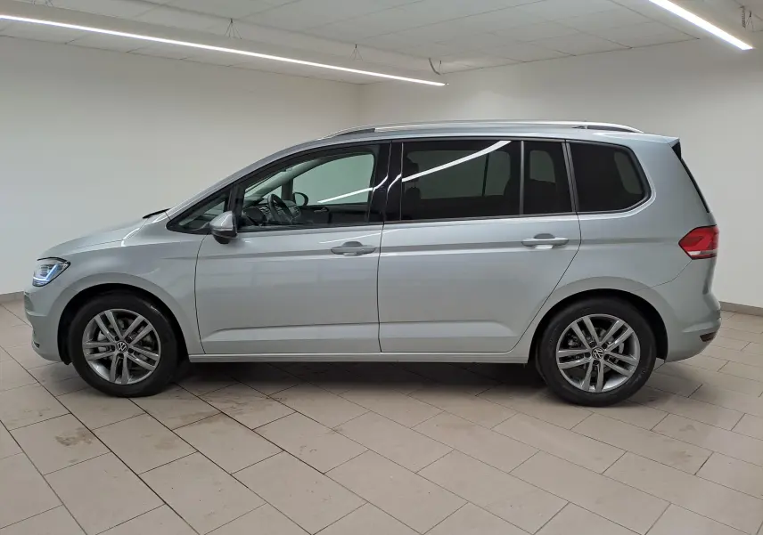 Profil droit d'un Volkswagen Touran 2025 argent Dolomite, avec jantes alliage et vitres teintées en intérieur neutre.