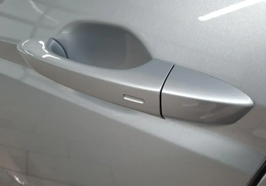 Poignée de porte côté droit du Volkswagen Touran 2025 en peinture métallisée Argent Dolomite, détail extérieur proche.